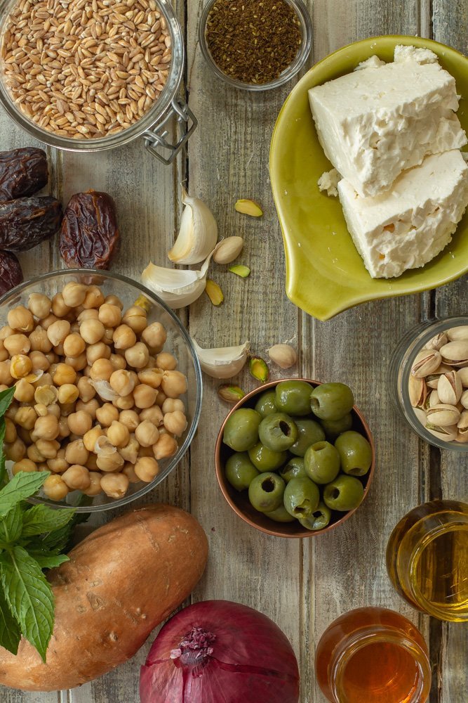 Fresh Mediterranean salad ingredients laid out on a wooden cutting board