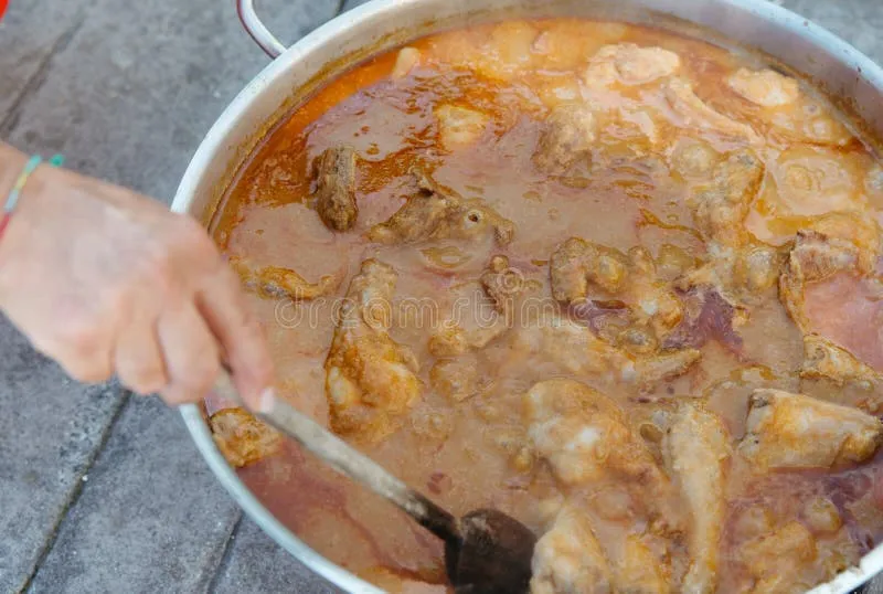 Close up of a wooden spoon stirring a bubbling pot of vegetable soup on a gas stove