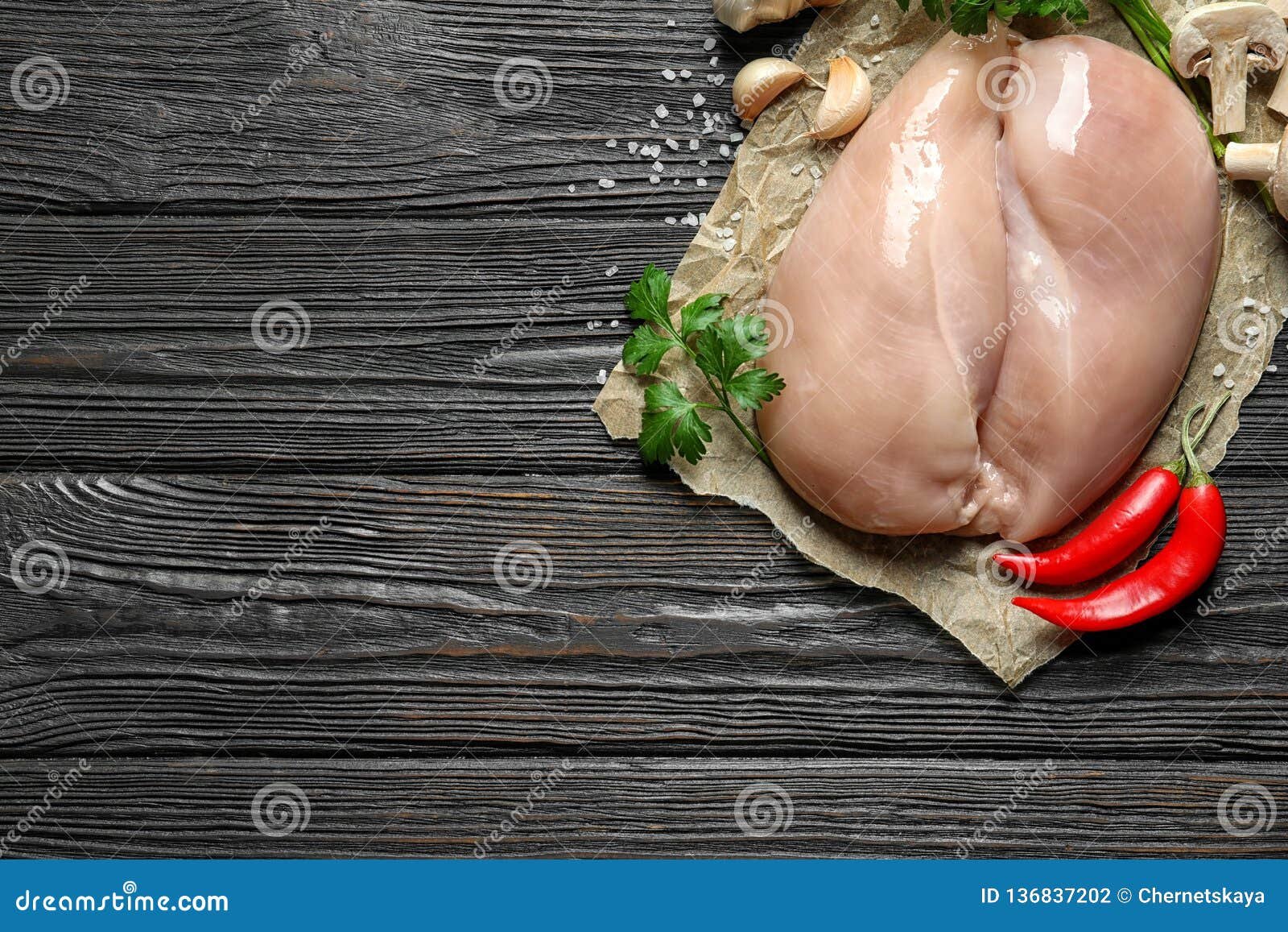 Raw chicken thighs seasoned with herbs and spices next to uncooked egg noodles